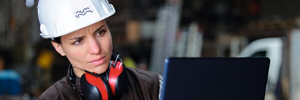 Female engineer wearing hard hat infront of computer in an industrial environment